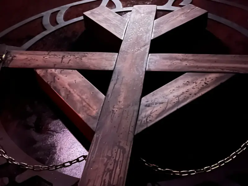 Umgedrehtes Holzkreuz über einem Ritualzeichen, an Ketten befestigt — Escape Room Sanctum in Freiburg